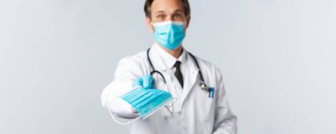 Covid-19, virüsü önleme, sağlık çalışanları ve aşı konsepti. Dost canlısı doktor, Coronavirus salgını sırasında sağlıklı kalabilmek için hasta maskesi takıyor. Doktor PPE 'yi veriyor.