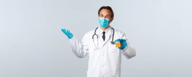 Covid-19, virüsü önleme, sağlık çalışanları ve aşı konsepti. Tıbbi maskeli ve eldivenli şok olmuş doktor idrar örneği ve omuz silkip hasta testini teşhis etti.