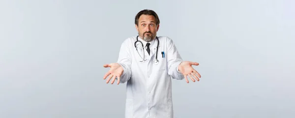 Covid-19, ξέσπασμα του ιού της στέψης, επαγγελματίες υγείας και πανδημία. Μπερδεμένοι άνδρες γιατρός έκανε λάθος εξηγώντας σε Hostal εργαζόμενος, δείχνοντας άδεια χέρια και shrugging — Φωτογραφία Αρχείου
