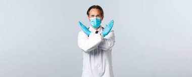 Covid-19, virüsü önleme, sağlık çalışanları ve aşı konsepti. Coronavirus 'la savaşan kararlı bir doktor ne yapmayacağını söyler, kollarını kavuşturur ya da yasaklama hareketi yapar.