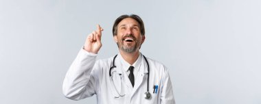 Covid-19, virüsü önleme, sağlık çalışanları ve aşı konsepti. İyimser, umutlu, beyaz önlüklü, şans dileyen, gülümseyen, dilek tutan doktorların yakın çekimi.