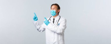 Covid-19, virüsü önleme, sağlık çalışanları ve aşı konsepti. Şaşırmış tıbbi maskeli ve eldivenli erkek doktor sol üstteki reklamı heyecanlı bir ifadeyle işaret ediyor.