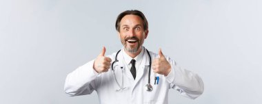 Covid-19, virüsü önleme, sağlık çalışanları ve aşı konsepti. Heyecanlı, heyecanlı, beyaz önlüklü doktor tamamen katılıyor. Onaylıyor, şaşırıyor ve gülümsüyor.