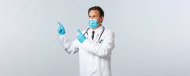 Covid-19, virüsü önleme, sağlık çalışanları ve aşı konsepti. Hüzünlü, kasvetli, tıbbi maskeli doktor kötü sonuçlar alıyor. Sol üst köşeden somurtuyor, kötü haberler yüzünden sıkıntılı.