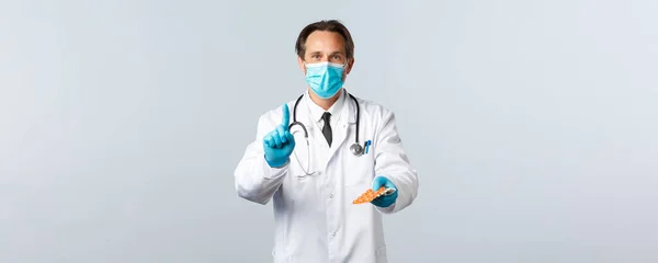 Covid-19, πρόληψη του ιού, εργαζόμενοι στον τομέα της υγείας και την έννοια του εμβολιασμού. Γιατρός με ιατρική μάσκα και γάντια εξηγεί συνταγή, δίνουν φάρμακα και δείχνουν ένα δάχτυλο, δίνοντας χάπια στον ασθενή — Φωτογραφία Αρχείου