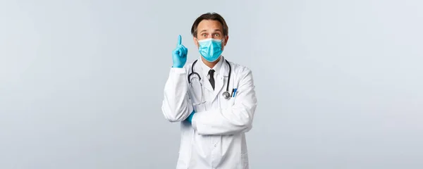 Covid-19, Prävention von Viren, Gesundheitspersonal und Impfkonzept. Aufgeregte männliche Arzt in medizinischer Maske und Handschuhen haben Lösung, Vorschlag über Coronavirus-Patienten, heben den Finger — Stockfoto