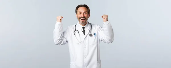 Covid-19 、コロナウイルスの発生、医療従事者およびパンデミックの概念。幸せな男性医師が良いニュースを受信します。,お祝いと笑顔で手を上げ満足,勝利 — ストック写真