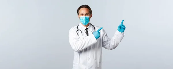 Covid-19: 바이러스 예방, 의료 종사자 및 예방 개념. 흰 코우 트 , 의학용 마스크 및 오른쪽 상단 광고를 가리키는 장갑을 낀 친절 한 의사, 흰 배경 — 스톡 사진