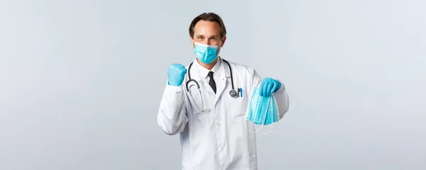 Covid-19, virüsü önleme, sağlık çalışanları ve aşı konsepti. Klinikte PPE giyen neşeli doktor hastane çalışanları için tıbbi maske aldı. — Stok fotoğraf