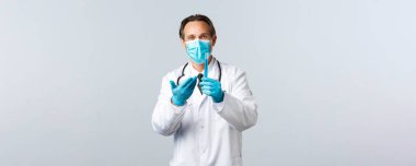 Covid-19, virüsü önleme, sağlık çalışanları ve aşı konsepti. Tıbbi maskeli ve eldivenli tatmin olmuş gülümseyen doktor test tüpünü aşı numunesiyle işaret ediyor, iyi sonuçtan memnun.