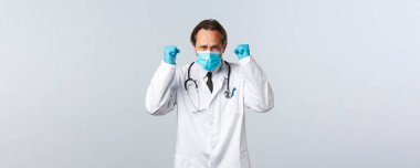 Covid-19, virüsü önleme, sağlık çalışanları ve aşı konsepti. Kararlı doktor hazır ol, hasta hastalarla kliniğe girmeden önce kendine güveni arttır, yumruklarını sık, maske tak ve eldiven tak.