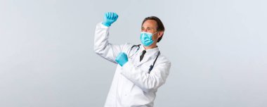 Covid-19, virüsü önleme, sağlık çalışanları ve aşı konsepti. Sağlık maskeli ve eldivenli başarılı doktor iyi haberleri kutluyor, yumruk tokuşturma ve dans, beyaz arka plan