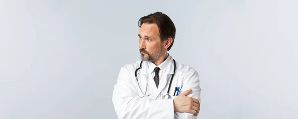 Covid-19, πρόληψη του ιού, εργαζόμενοι στον τομέα της υγείας και την έννοια του εμβολιασμού. Στοχαστικός γιατρός με λευκό παλτό και στηθοσκόπιο, κοιτάζει αριστερά ανήσυχος, σκέφτεται, παίρνει σημαντικές αποφάσεις — Φωτογραφία Αρχείου