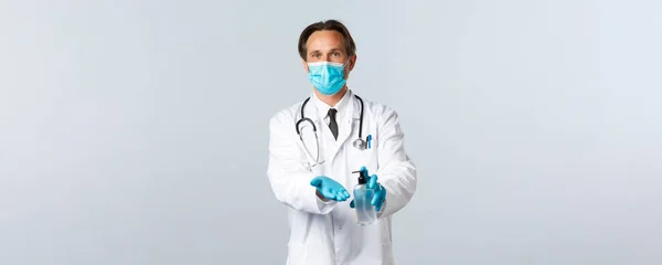 Covid-19, πρόληψη του ιού, εργαζόμενοι στον τομέα της υγείας και την έννοια του εμβολιασμού. Γιατρός σε ιατρική μάσκα και γάντια εξηγούν σημαντικό της υγιεινής, χρησιμοποιώντας απολυμαντικό χεριών κατά τη διάρκεια της επιδημίας του κορωναϊού — Φωτογραφία Αρχείου
