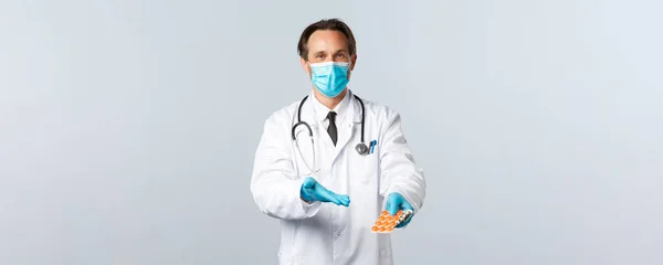 Covid-19, Prävention von Viren, Gesundheitspersonal und Impfkonzept. Freundlicher Arzt in medizinischer Maske und Handschuhen, die auf Medikamente zeigen, empfiehlt die Verwendung dieser Pillen gegen Grippe — Stockfoto