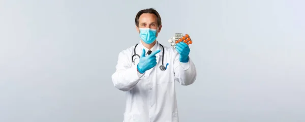 Covid-19: 바이러스 예방, 의료 종사자 및 예방 개념. 약사는 약물 치료를 권 한다. 의료용 마스크와 알약을 가리키는 장갑을 낀 의사는 약을 처방 한다 — 스톡 사진