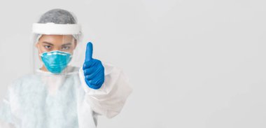 Covid-19, koronavirüs hastalığı, sağlık çalışanları konsepti. Ciddi görünümlü, kendine güvenen Asyalı kadın doktor, solunum cihazında kişisel koruyucu ekipman hekimi, baş parmaklarını yukarı kaldır, beyaz arka plan