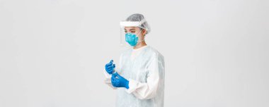 Covid-19, koronavirüs hastalığı, sağlık çalışanları konsepti. Ciddi genç Asyalı kadın doktor, kişisel koruyucu ekipman doktoru aşı ile ampul içine şırınga yerleştirin