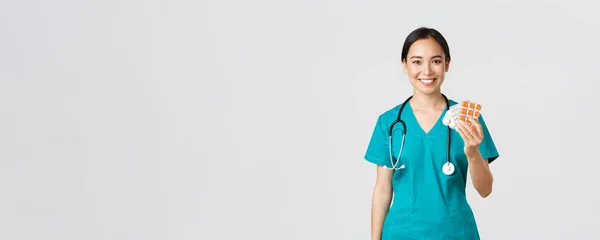 Egészségügyi dolgozók, vírusmegelőzés, karantén kampány koncepció. Barátságos kinézetű ázsiai nővér, orvos magyarázza a beteg gyógyszeres kezelés, bemutató gyógyszerek és mosolygós, fehér háttér — Stock Fotó