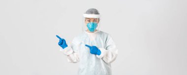 Covid-19, koronavirüs hastalığı, sağlık çalışanları konsepti. Şaşırmış kadın Asyalı doktor, tıbbi solunum cihazı hekimi ve sol üst köşeyi gösteren kişisel koruyucu ekipman.