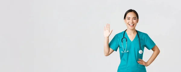 Covid-19 、医療従事者とウイルスの概念を防止します。親切な笑みを浮かべてアジアの女性医師は、医師の手を手を振ってこんにちは、挨拶患者、あなたを参照してくださいにいい — ストック写真