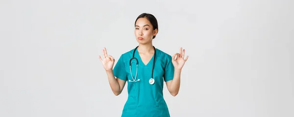 Covid-19 、医療従事者、パンデミックの概念。頭蓋骨の中にアジア系女性看護師の印象的な,医師は正しいジェスチャーを示し、承認にうなずきます,優れた選択を賞賛,誰かを褒めます — ストック写真