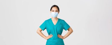 Covid-19, koronavirüs hastalığı, sağlık çalışanları konsepti. Neşeli gülümseyen Asyalı kadın doktor, önlüklü ve tıbbi maskeli doktor, neşeli görünüyor, hastalarla hastanede çalışıyor.