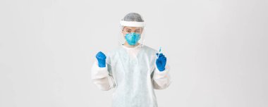 Covid-19, koronavirüs hastalığı, sağlık çalışanları konsepti. Kararlı ve kendinden emin Asyalı kadın doktor, teknoloji laboratuarı çalışanı kişisel koruyucu ekipman elinde aşı şırıngası tutuyor.