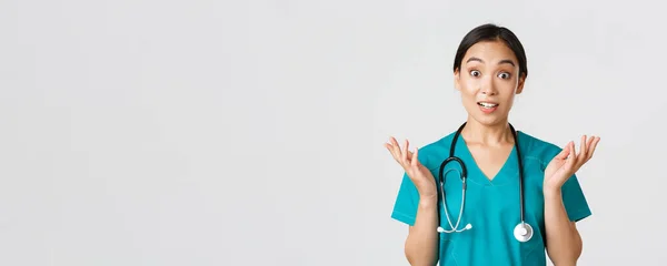 Sağlık çalışanları, virüsü önleme, karantina kampanyası konsepti. Şaşırmış ve eğlenmiş, mutlu Asyalı kadın hemşire, doktor harika haberler duyup, ellerini kaldırıp kameraya bak. — Stok fotoğraf