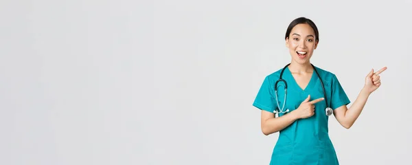 Covid-19, pracownicy służby zdrowia, koncepcja pandemii. Cieszy uśmiech, piękny azjatycki lekarz, terapeutka w fartuchu lub pielęgniarka wskazująca palcem górny prawy róg, wskazując drogę do pacjenta, białe tło — Zdjęcie stockowe