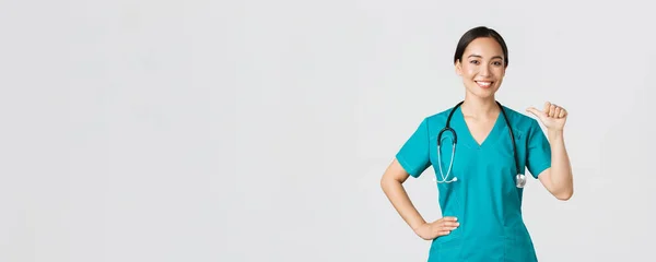 Covid-19, egészségügyi dolgozók, világjárvány. Szakmai magabiztos női ázsiai orvos, ápolónő köpenyben mutat magára, és mosolyog, garantálja, hogy tudja, mit csinál, fehér háttér — Stock Fotó