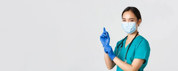 Covid-19, coronavirus disease, healthcare workers concept.专业自信的亚洲女医生，戴着医疗面罩和刷子的护士，戴上橡胶手套检查，白色背景 — 图库照片
