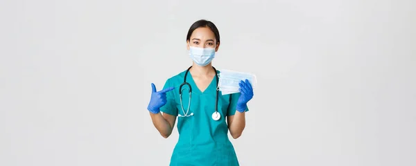 Covid-19, coronavirus disease, healthcare workers concept.用橡胶手套和刷子微笑亚洲女医生、医生或护士，用手指指指医疗面罩对病人的安全 — 图库照片