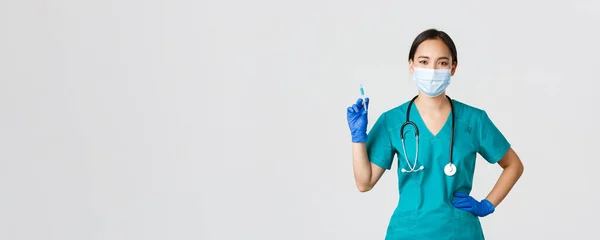 Covid-19, coronavirus disease, healthcare workers concept.自信的亚洲女护士，戴着医疗面罩和橡胶手套的医生，拿着装有疫苗的注射器，站在白底 — 图库照片