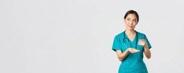 Sağlık çalışanları, virüsü önleme, karantina kampanyası konsepti. Düşünceli, düşünceli, gülümseyen Asyalı kadın hemşire, önlüklü stajyer hastaya ilaç veriyor ve sol üst köşede rüya gibi görünüyor.