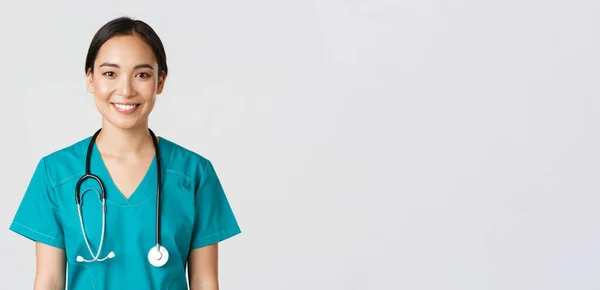 Healthcare workers, preventing virus, quarantine campaign concept. Close-up of smiling pleasant asian female nurse, physician in scrubs looking upbeat, listening to patient, white background — Stock Photo, Image
