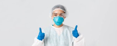 Covid-19, koronavirüs hastalığı, sağlık çalışanları konsepti. Kendine güvenen profesyonel Asyalı doktor, teknoloji laboratuarı çalışanı kişisel koruma ekipmanları onaylandı.