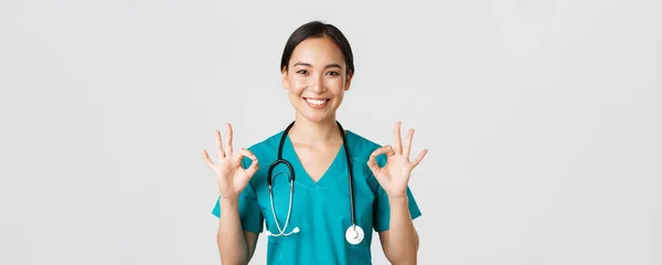 Gesundheitshelfer, Virusprävention, Kampagnenkonzept für Quarantäne. Zufrieden gut aussehende asiatische Krankenschwester, Arzt zeigt okay Geste in Zustimmung, empfehlen oder garantieren perfekten Service — Stockfoto