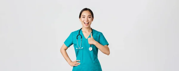 Covid-19, pracownicy służby zdrowia, koncepcja pandemii. Uśmiechnięta, pewna siebie kobieta azjatycka pielęgniarka w fartuchu ma wszystko pod kontrolą, wykazują się akceptacją, gwarantują jakość usług w klinice — Zdjęcie stockowe