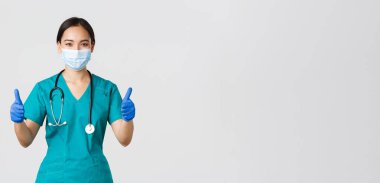 Covid-19, koronavirüs hastalığı, sağlık çalışanları konsepti. Kendine güvenen profesyonel doktor, Asyalı doktor, kişisel koruyucu ekipman, hastaya garanti ve güvence, tıbbi maske takın.