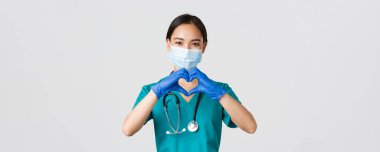 Covid-19, koronavirüs hastalığı, sağlık çalışanları konsepti. Çekici gülümseyen Asyalı kadın doktor, tıbbi maskeli doktor ve lastik eldiven, hastalara bakım, kalp hareketi