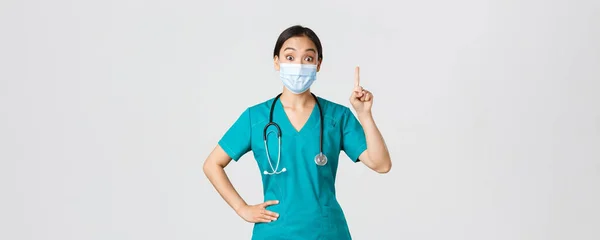 Covid-19, choroba koronawirusowa, koncepcja pracowników służby zdrowia. Podekscytowany azjatycki lekarz, lekarz w masce medycznej i peeling mają sugestię, podnosząc palec wskazujący gest eureka, białe tło — Zdjęcie stockowe