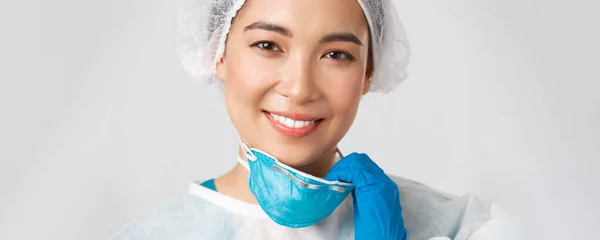 Covid-19, onemocnění koronavirem, koncept zdravotnických pracovníků. Detailní záběr s nadějí šťastný usměvavý asijský lékař v osobní ochranné prostředky, vzlet respirátor a mají kožní poškození — Stock fotografie