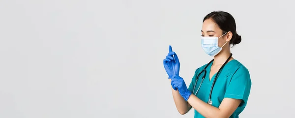 Covid-19, coronavirus disease, healthcare workers concept.专业微笑的亚洲女护士，穿着洗涤剂和医用面罩的医生，戴上橡胶手套进行检查、病人检查 — 图库照片