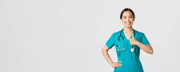 Covid-19, pracownicy służby zdrowia, koncepcja pandemii. Uśmiechnięta, pewna siebie kobieta azjatycka pielęgniarka w fartuchu ma wszystko pod kontrolą, wykazują się akceptacją, gwarantują jakość usług w klinice — Zdjęcie stockowe
