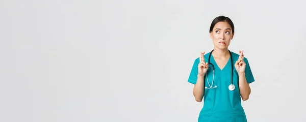 Covid-19, pracownicy służby zdrowia, koncepcja pandemii. Nadzieja nerwowy azjatycki kobieta stażysta w fartuch czeka na wiadomości, lekarz kciuki palce i gryzienie wargi jak patrząc w lewym górnym rogu, modląc się — Zdjęcie stockowe
