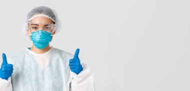 Covid-19, koronavirüs hastalığı, sağlık çalışanları konsepti. Kendine güvenen profesyonel Asyalı doktor, teknoloji laboratuarı çalışanı kişisel koruma ekipmanları onaylandı.
