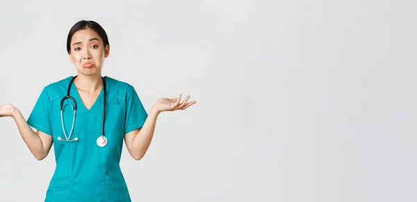 Ковид-19, медицинские работники, пандемия. Портрет невежественной азиатской медсестры, женщина-врач пожимает плечами и раздвигает руки боком, не знаю, не могу помочь, белый фон — стоковое фото