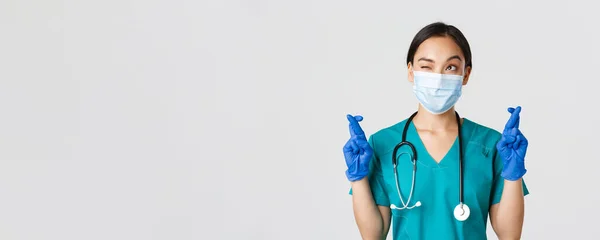 Covid-19, coronavirus disease, healthcare workers concept.有希望的亚洲女医生，戴着医疗面具和手套，向左上角望望，祈祷，许愿，白色背景 — 图库照片