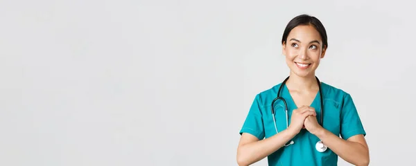 Gezondheidswerkers, het voorkomen van virussen, quarantaine campagne concept. Vastberaden en zelfverzekerd aziatische vrouwelijke arts in scrubs, knijpen handen tegen elkaar, klaar, op zoek linksboven hoek — Stockfoto